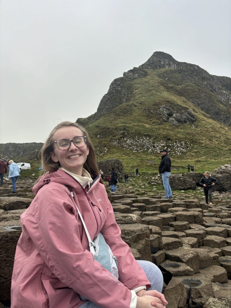 Macy Morgan sitting on rock formations at the Giant's Causeway in Northern Ireland.