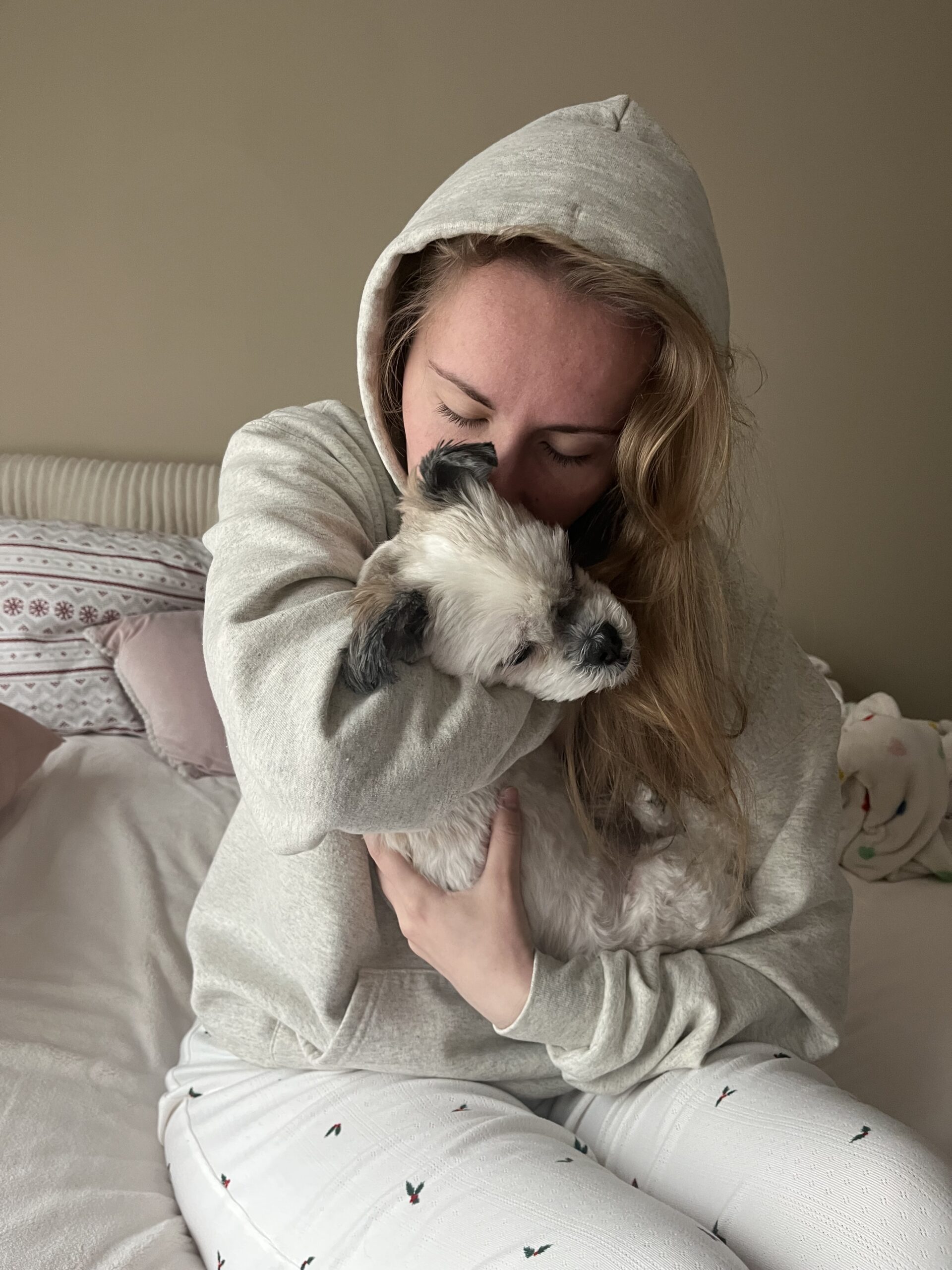 Macy Morgan (author) sitting on a bed holding her dog.