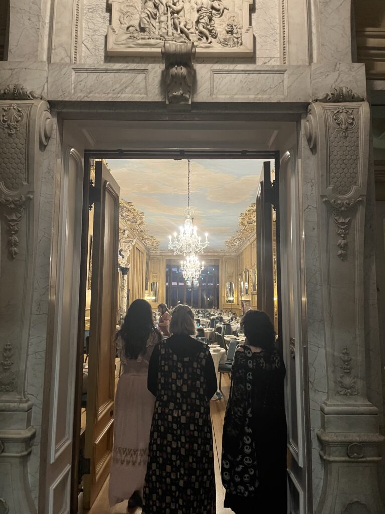 A photo looking into the doorway of a large stateroom in Harlaxton Manor, behind three friends who made it easier to mitigate culture shock while abroad.