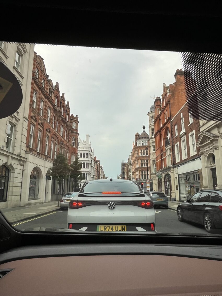 A view of a street in London from the inside of a cab, facing out the front windshield.